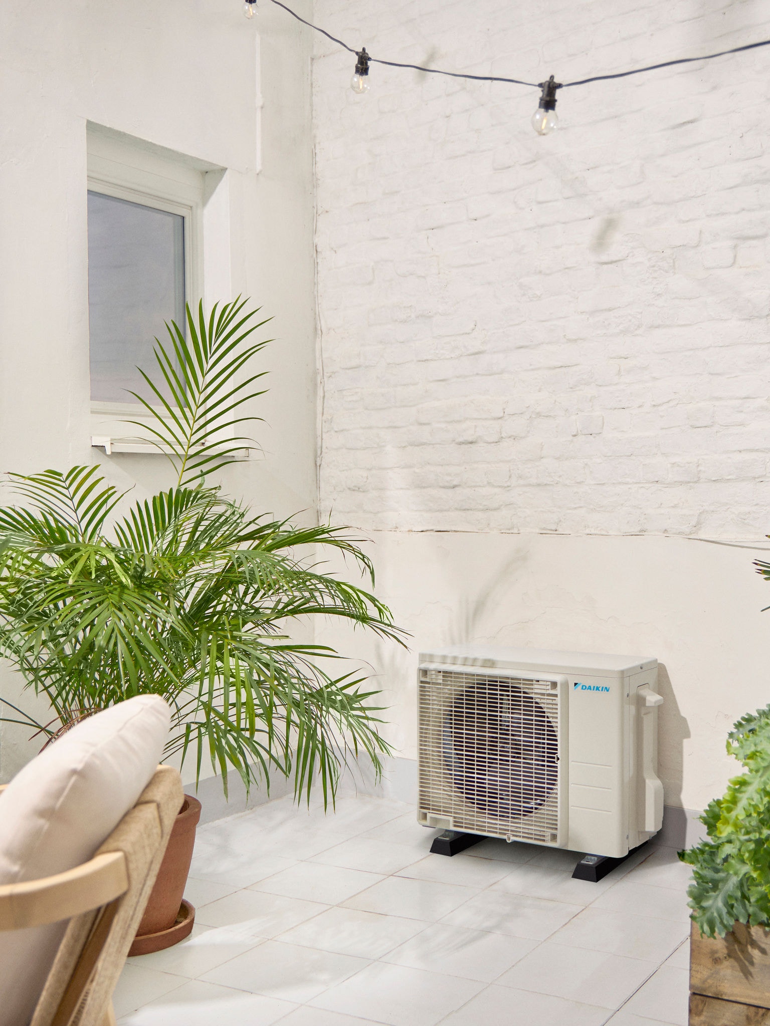 Надворешна единица Daikin на бела тераса со растение