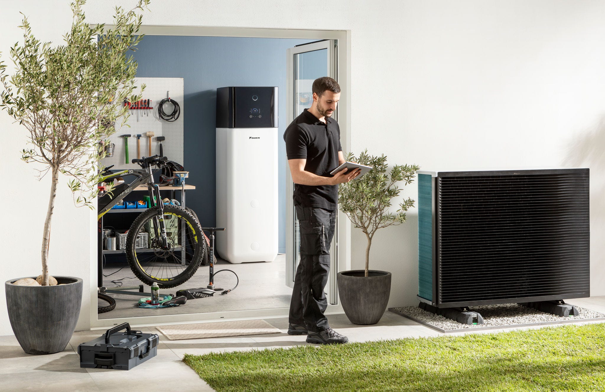 Инсталатер ја проверува надворешната единица и резервоарот за топла вода на топлинска пумпа со воздух како извор на енергија