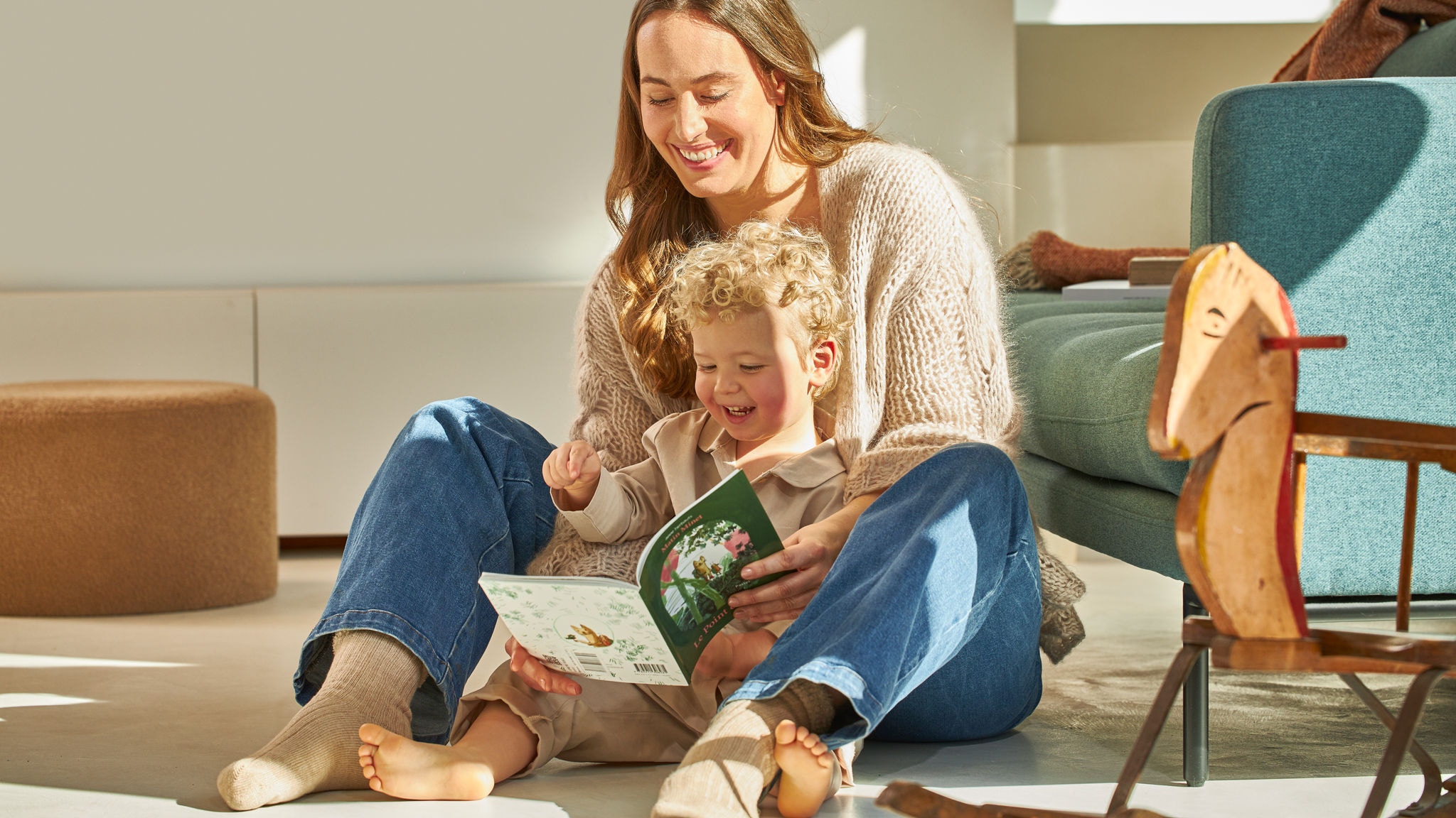 Мајка и синче седат насмеани и гледаат во книга