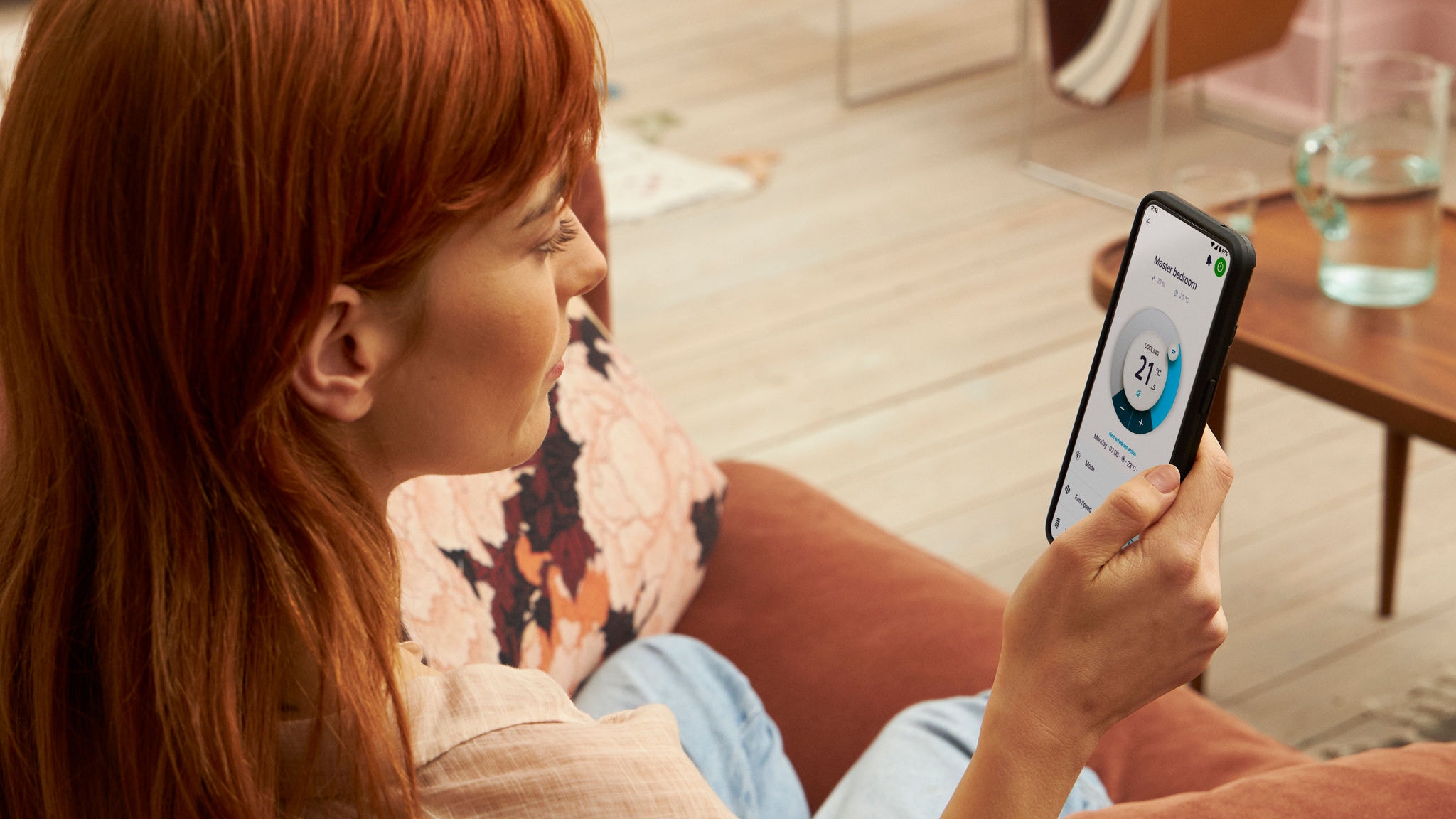 Госпоѓа држи паметен телефон и ја користи апликацијата Onecta за да ја контролира собната температура