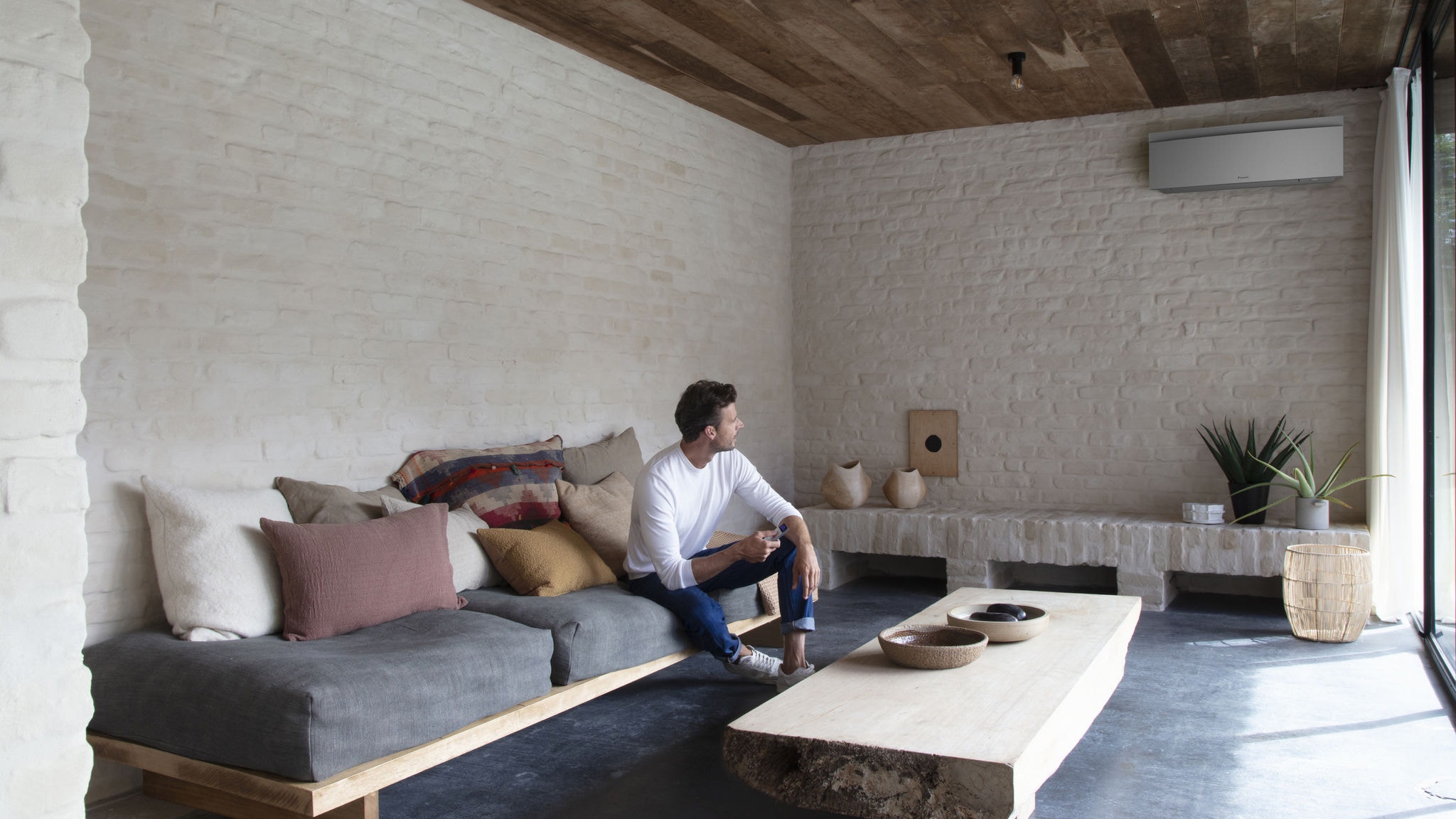 Човек го контролира својот клима уред во дневната соба со далечински управувач