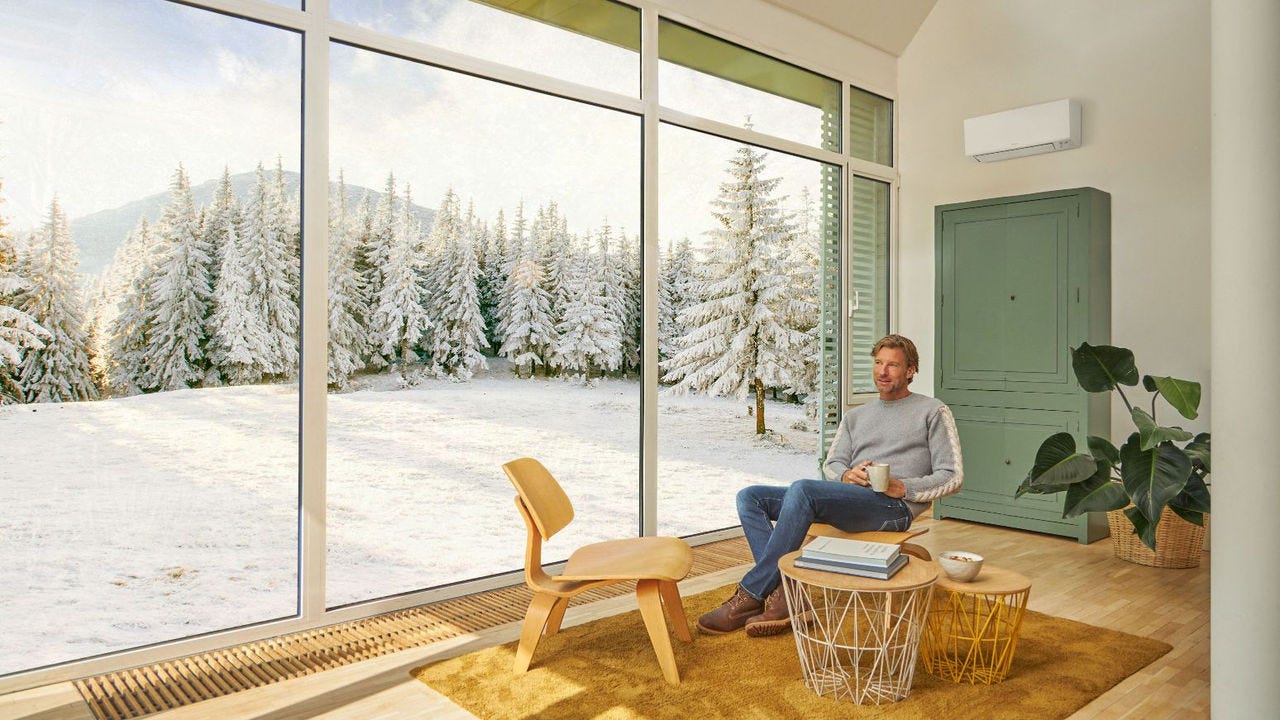 Човек седи на кауч и ужива во греење со клима уред