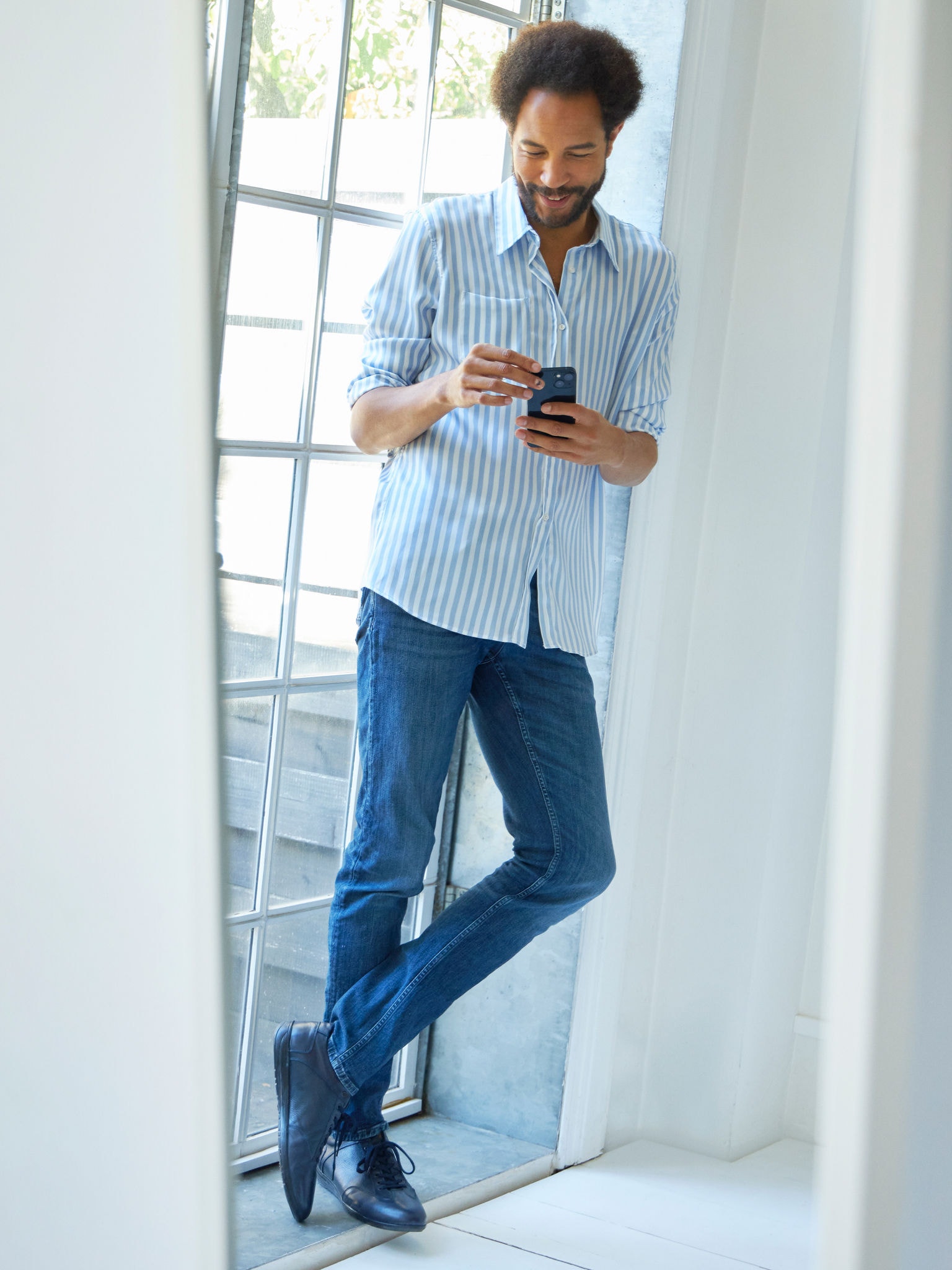 Човек стои близу до прозорец и гледа клима уреди на центарот за виртуелно искуство на својот паметен телефон