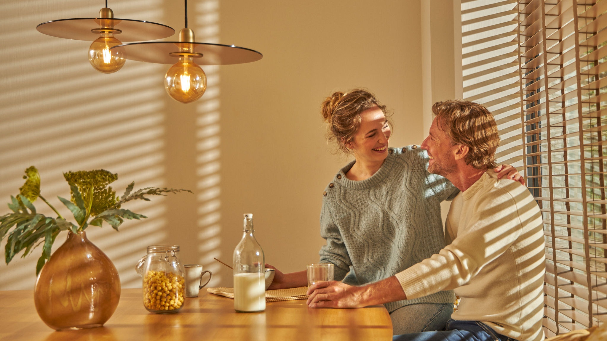 Двојка ужива во удобен појадок заедно во својата удобно топла кујна, благодарение на оваа интуитивна технологија на греење