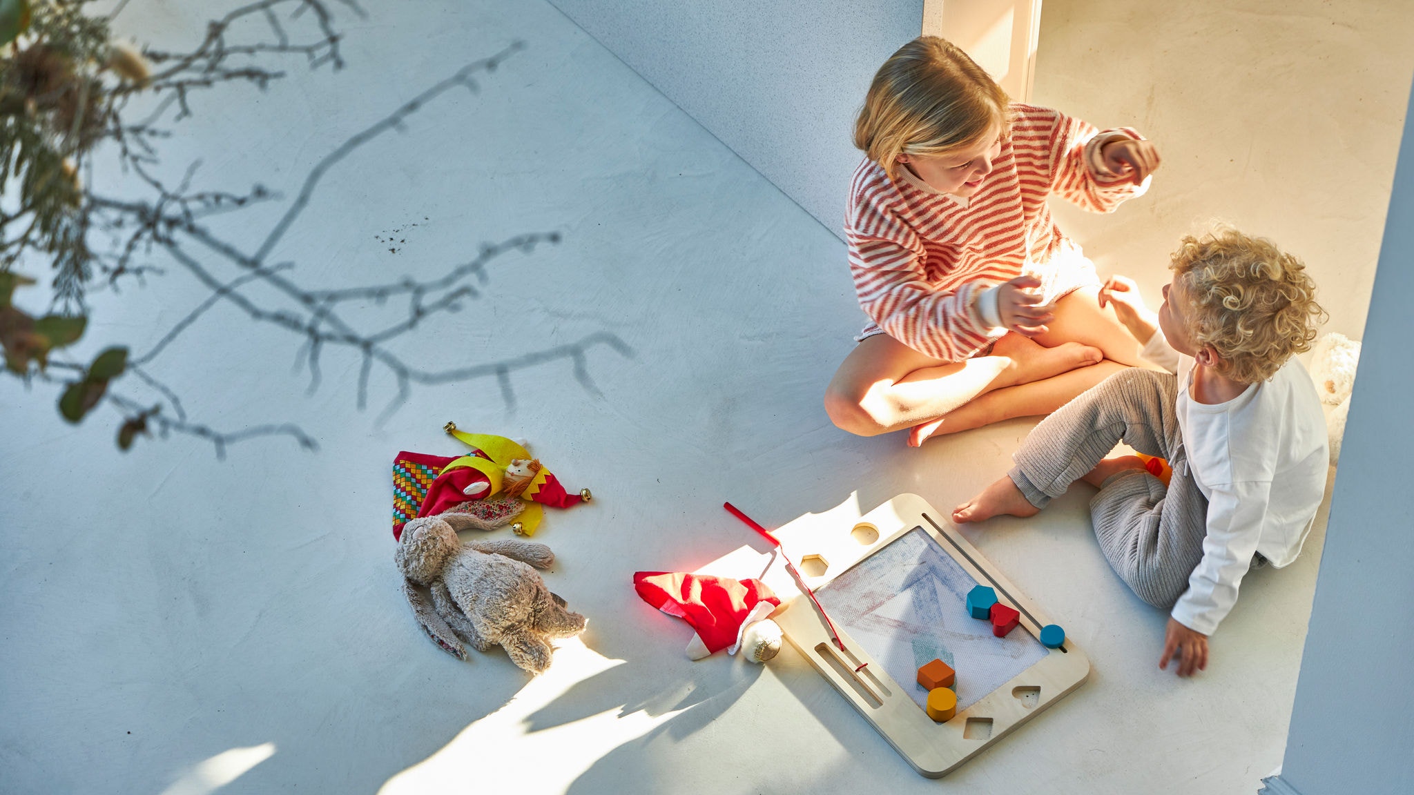 Брат и сестра си играат на земјата и уживаат во удобната температура којашто ја обезбедува геотермалната топлинска пумпа Daikin