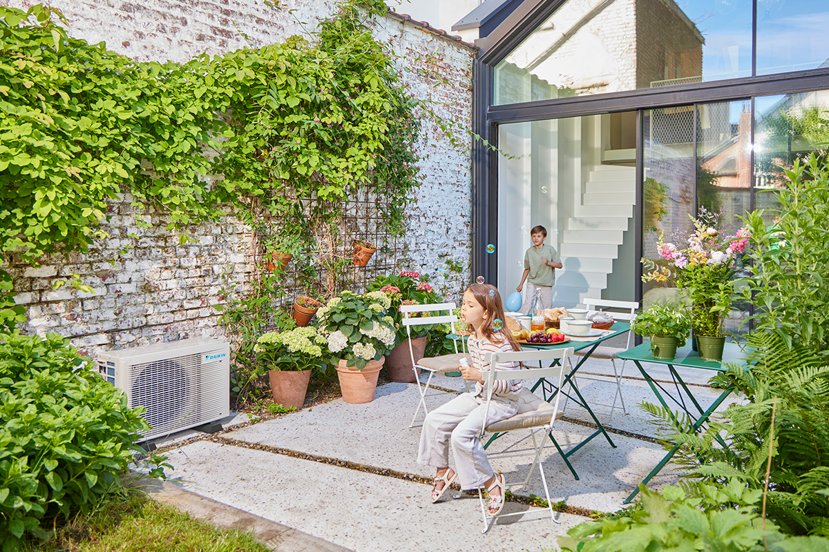 Деца играат џамлии на тераса до надворешна топлинска пумпа