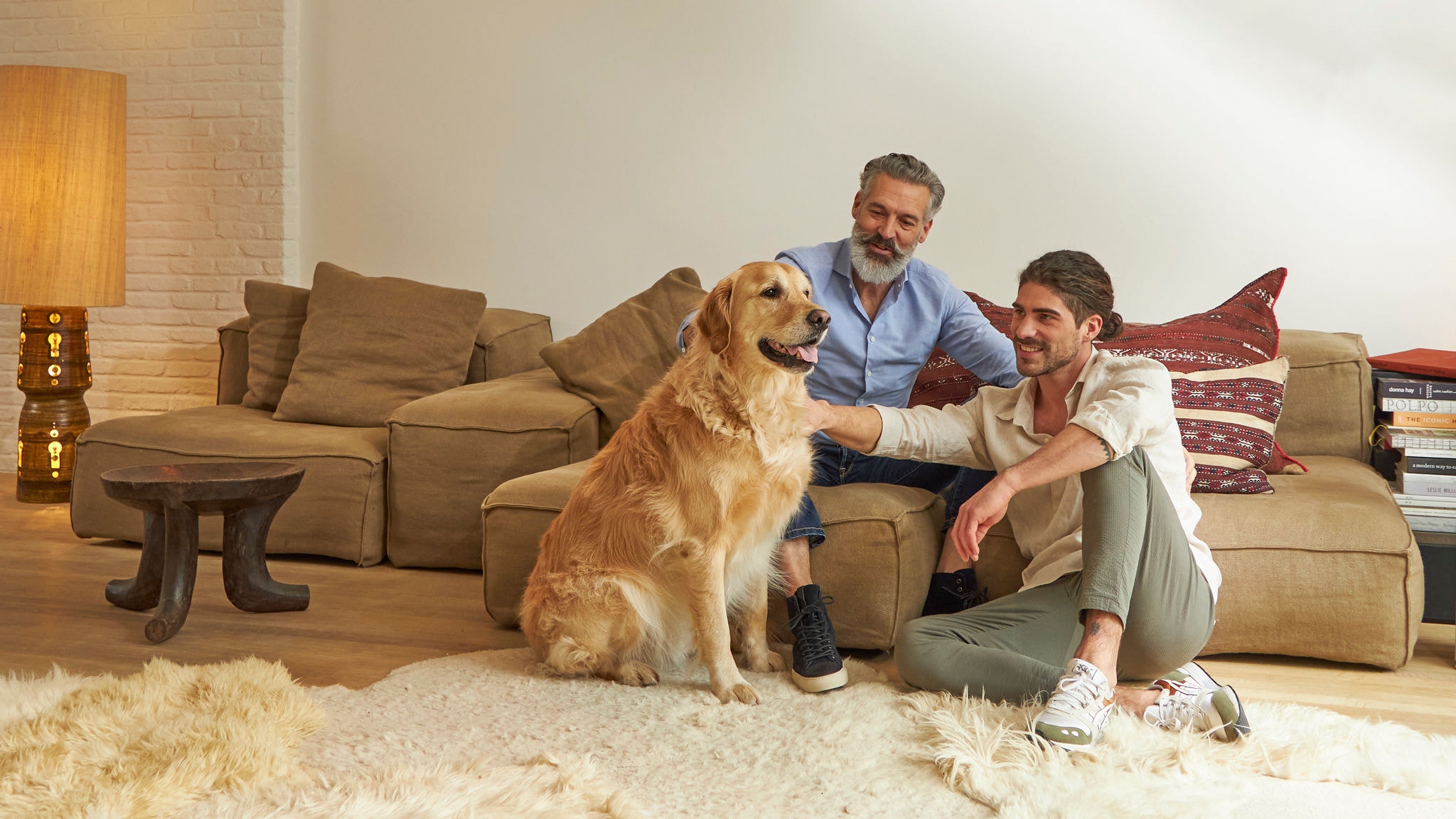 Two men petting a dog in their cosy air conditioned living room