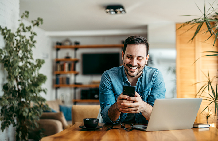 Човек гледа во својот мобилен телефон во својот дом